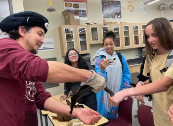 A man holds a Pacific lamprey, an eel-like fish, as it touches the hand of a female student at a middle school.