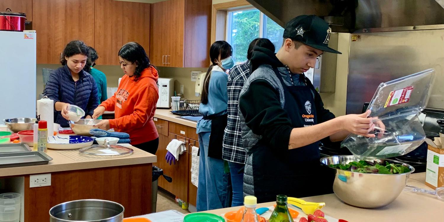 Teens work together in a kitchen preparing food, surrounded by ingredients and cooking supplies on the counter.