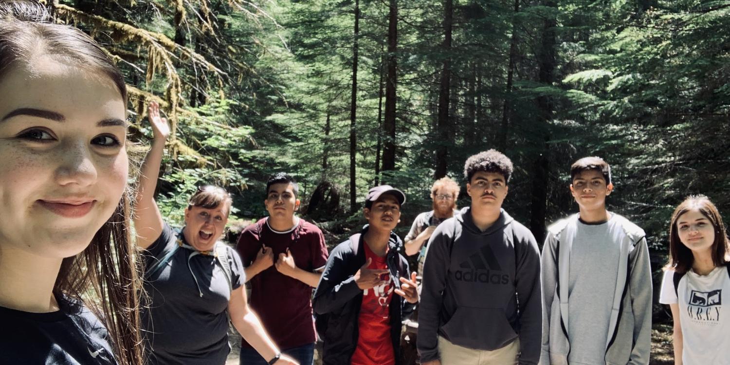 Teenagers on a hike in the woods pose for a group photo.