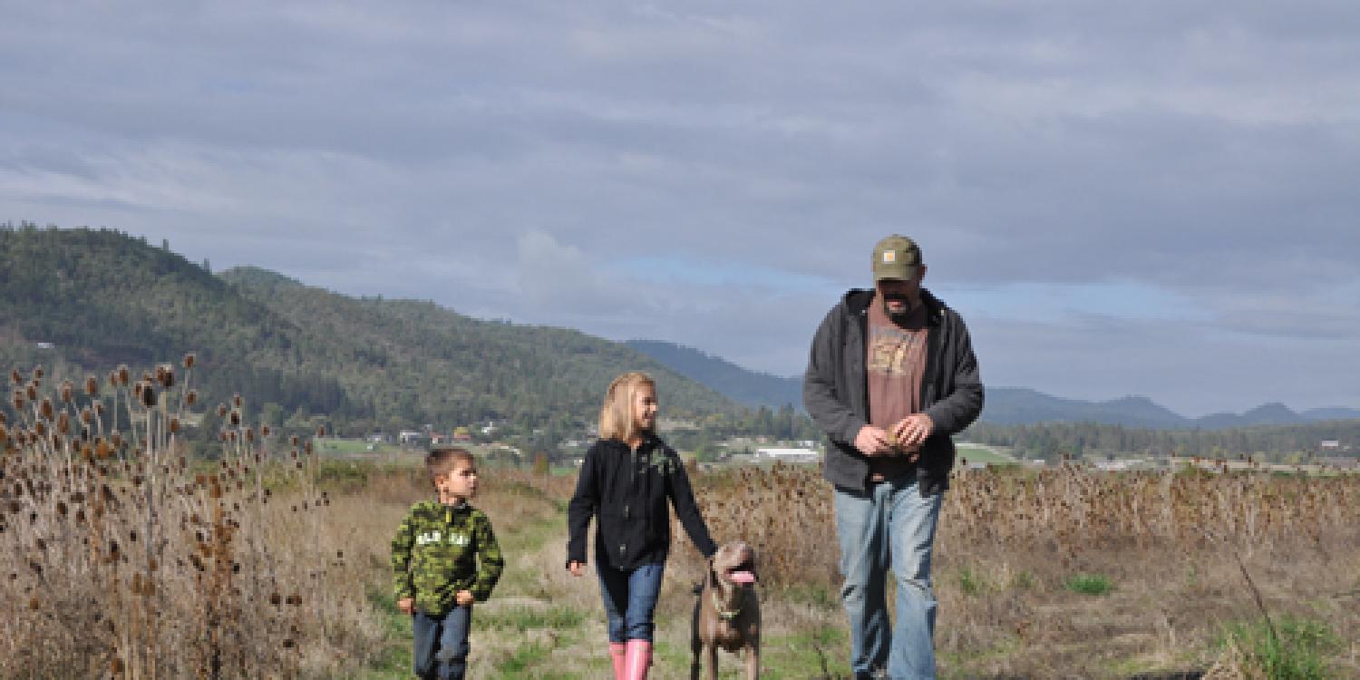 Land Steward Russell Kockx (far right) and his children walk along their property in Central Point, Ore.