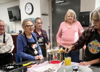 Master Food Preserver trainees Kathy Morris (from left) and Jean Newman and Master Food Preserver mentors Diane Hyde and Janice Gregg watch Master Food Preserver trainee Kelly Muller learn how to hot pack pineapple for the steam canner.