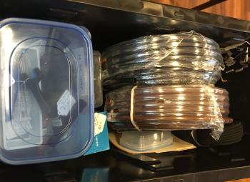 Coiled tubing, connectors, and a plastic container are organized in a bin as part of a drip irrigation kit.