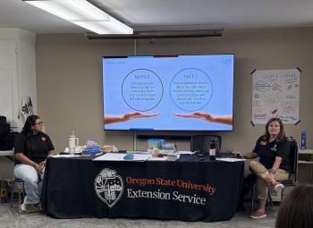 Two Oregon State University Extension Service educators lead a youth suicide prevention training, with a slide on myths and facts about asking directly about suicidal thoughts displayed on a screen.