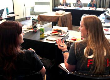 Participants discuss ideas during a wildfire adaptation workshop, seated around tables with notebooks and materials.