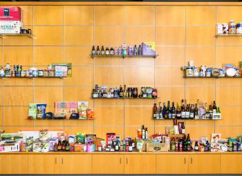 A large display wall features shelves of Oregon-made food and beverage products, including packaged foods, jars, bottles and boxes arranged across a wood-paneled backdrop.