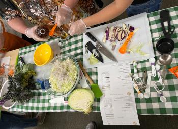 Participants in Fruits and Veggies for Families are chopping cabbage and pouring vinegar into a measuring cup