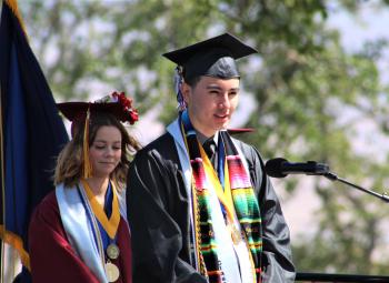 Wearing a black mortarboard and gown, Yahir Santillan-Guzman stands on a stage while he delivers his valedictory speech at The Dalles High School graduation in June.